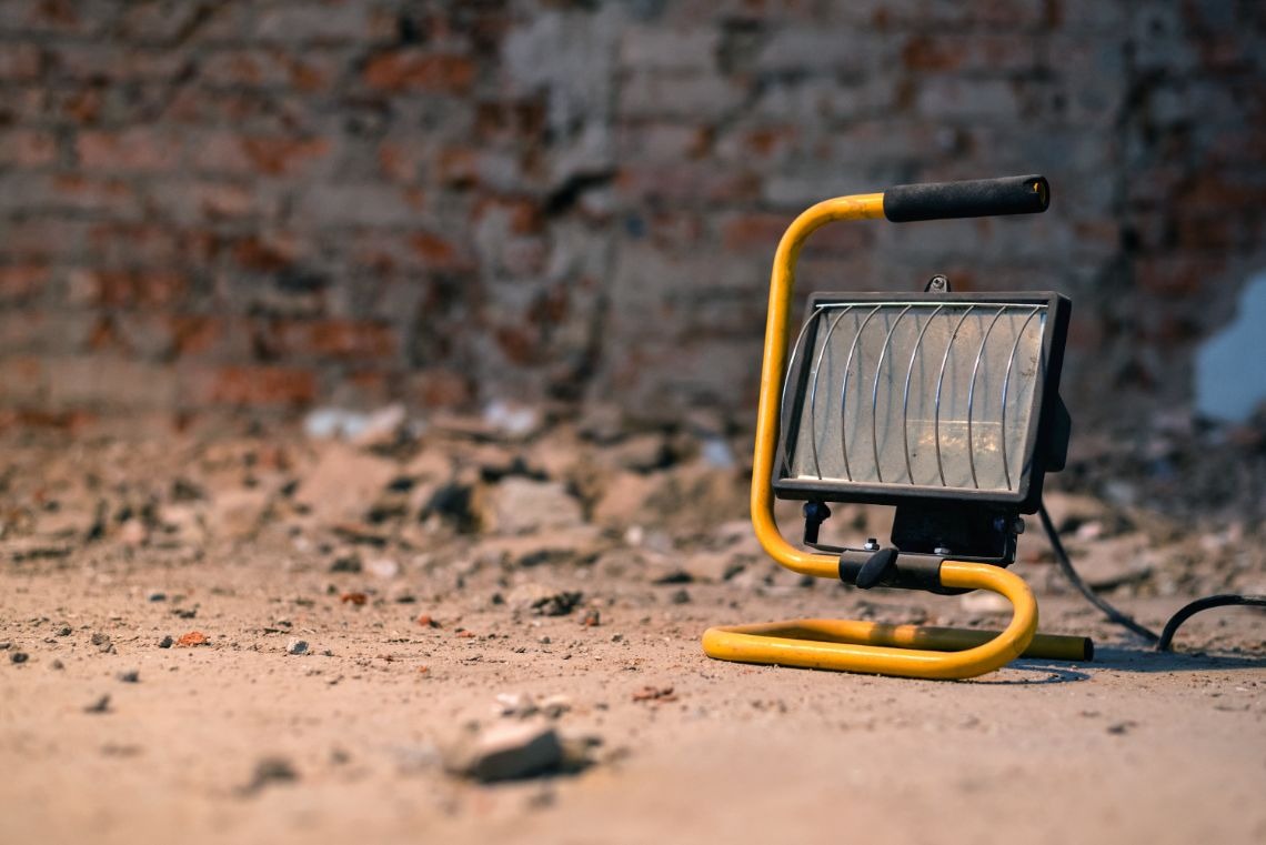 Lampa halogenowa budowlana stoi wśród gruzów